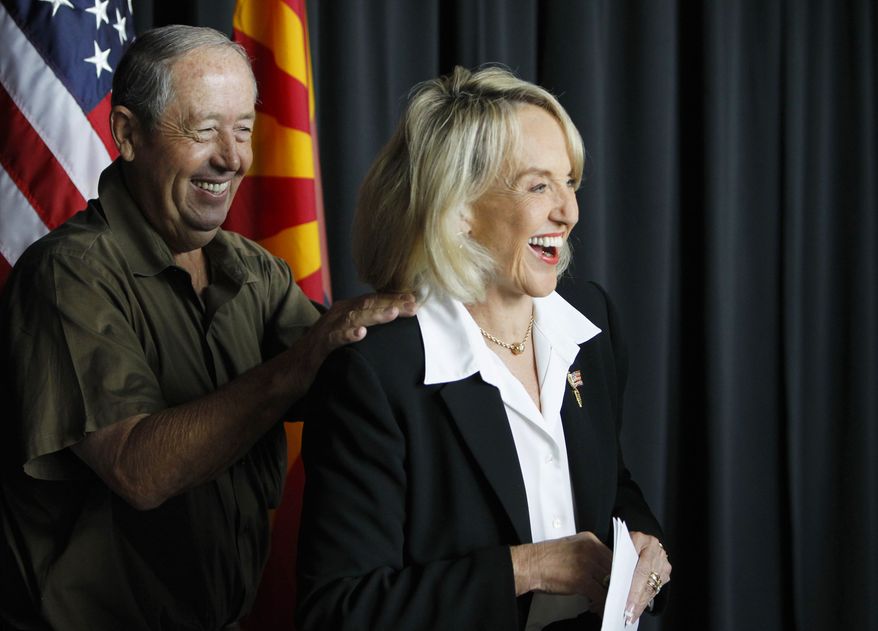 Arizona Republican Gov. Jan Brewer, right, smiles as Max Wilson, Maricopa County Board of Supervisors representing District 4, pats the governor on the back at a news conference in Glendale, Ariz., Friday, July 30, 2010. Brewer and Arizona Sen. John McCain held the news conference in the Phoenix suburb of Glendale to applaud a U.S. Air Force decision to base new F-35 combat jets at Luke Air Force Base in Glendale, but the event abruptly ended when the barrage of questions were regarding the Arizona immigration law and the next steps the governor was taking in the court battle. (AP Photo/Ross D. Franklin)