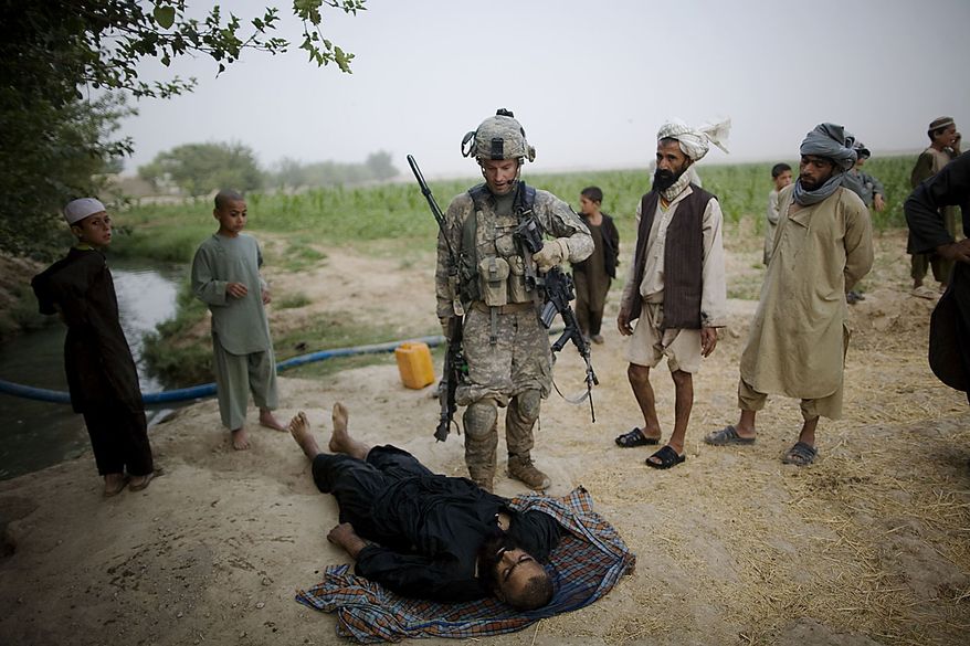 In this July 28, 2010, file photo, U.S. Army Lt. Christopher Babcock looks at the body of a suspected Taliban fighter killed by U.S. soldiers from 1-320th Alpha Battery, 2nd Brigade of the 101st Airborne Division, while local people protest the man was a farmer from Samir Kalacha village in the volatile Arghandab Valley, Kandahar, Afghanistan. (AP Photo/Rodrigo Abd, File)