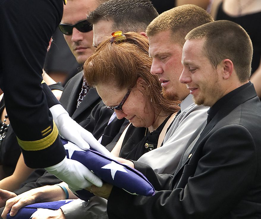 In this July 19, 2010, file photo, family members receive flags during a funeral service for Missouri Army National Guard Sgt. Robert Wayne Crow in Liberty, Mo. Crow, 42, of Kansas City, Mo., died July 10 in Paktika, Afghanistan, of wounds suffered when insurgents attacked his vehicle with an improvised explosive device. NATO announced Friday, July 30, 2010, that six more U.S. troops have died in Afghanistan, bringing the death toll for July to at least 66 and surpassing the previous month's record as the deadliest for American forces in the nearly 9-year-old war. (AP Photo/Charlie Riedel, File)
