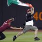 A Citi Field security guard tries to tackle a young man carrying a Mexican flag who ran onto the field in the seventh inning of the New York Mets vs the Arizona Diamondbacks baseball game at Citi Field in New York, Friday, July 30, 2010. (AP Photo/Paul J. Bereswill)