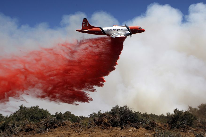 A tanker drops fire retardant on the crest of Hauser Peak in Palmdale, Calif., on Friday, July 30, 2010. (AP Photo/Damian Dovarganes)