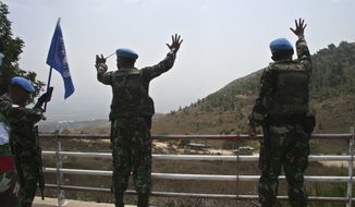 U.N. peacekeepers gesture as Israeli troops patrol the border fence in the southern border village of Adaisseh, Lebanon, Tuesday, Aug. 3, 2010. Lebanon and Israeli troops exchanged fire on the border Tuesday in the most serious clashes since a fierce war four years ago, and Lebanon said at least two of its soldiers were killed in shelling, authorities said. (AP Photo/Lutfallah Daher)