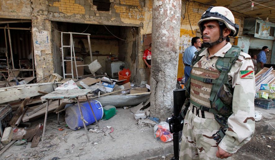 An Iraqi solider stands guard at the scene of an attack in Kut, southeast of Baghdad, on Wednesday. A car bomb ripped through a market in the deadliest of a series of attacks that killed and injured scores on Tuesday, officials said. (Associated Press)