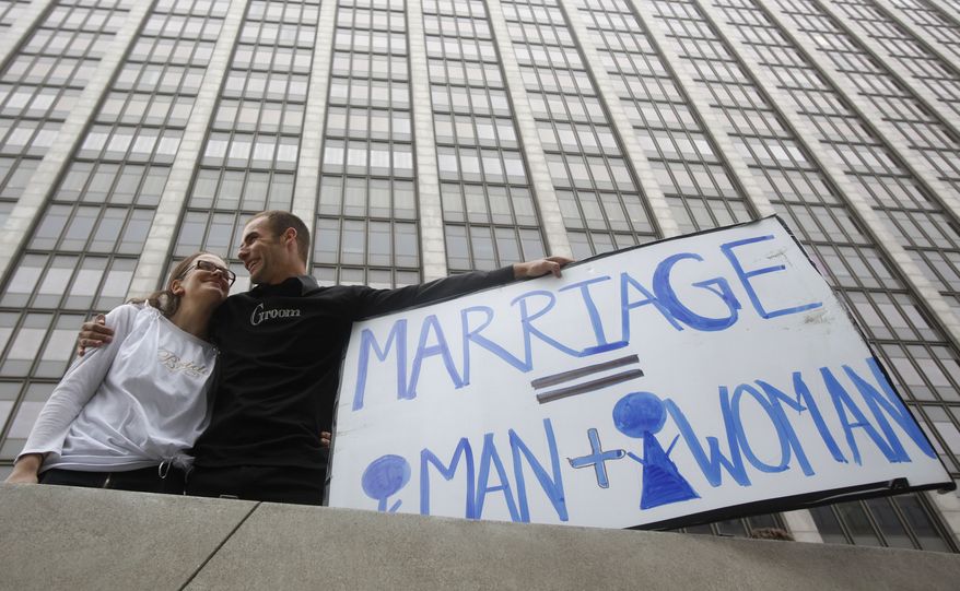 Nadia Chayka and her fiance, Luke Otterstad, both proponents of Proposition 8, hold up a sign outside of the Phillip Burton Federal Building in San Francisco on Wednesday. Chief U.S. District Judge Vaughn Walker ruled that Proposition 8, by defining marriage as the union of one man and one woman, violated the Due Process and Equal Protection clauses of the Constitution. (Associated Press)
