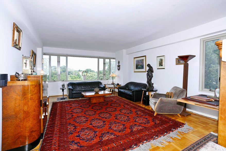 The living room has a wall of windows as well as a glass door leading to a balcony with a wrought-iron railing. The hardwood flooring has been restored to its original beauty.