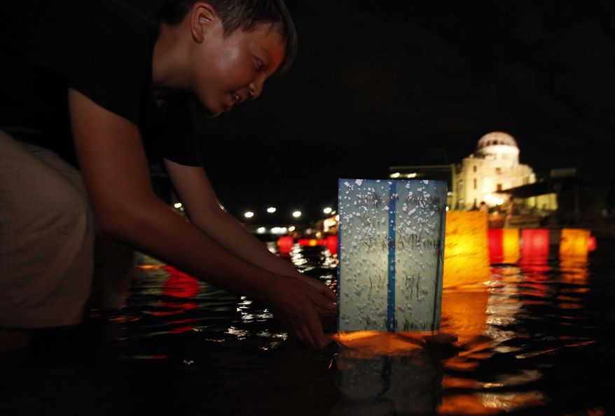 With the gutted Atomic Bomb Dome in the background, a boy releases a paper lantern on the Motoyasu River for a memorial service of the atomic bomb victims in Hiroshima, western Japan, Friday, Aug. 6, 2010. Hiroshima marks the 65th anniversary of the the world's first atomic bomb attack that devastated the western Japanese city at the closing days of World War II. (AP Photo/Shuji Kajiyama)