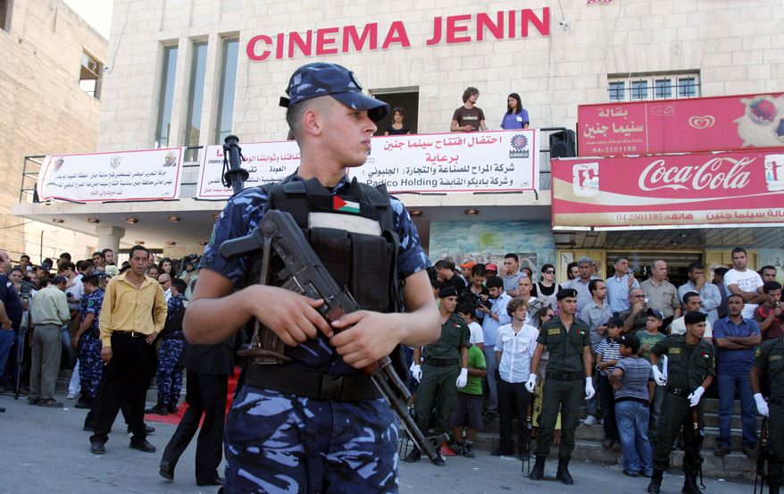 A police officer guards Cinema Jenin as Palestinians gather for its opening. The movie house, a rare commodity in the West Bank, marks a milestone in the shift of Jenin from a hub for Palestinian gunmen to a growing city. (Associated Press)