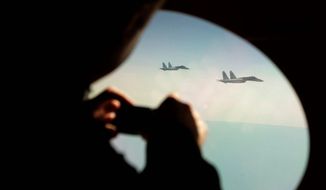 FILE: A colonel in the Canadian Forces takes photos through the window of a civilian aircraft playing the role of a hijacked airliner as it is escorted by two Su-27 Russian fighter jets. (Associated Press)