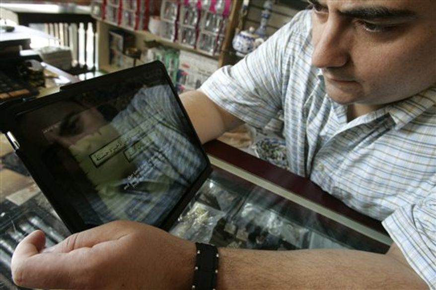 Jim Otun of Fairfield, N.J. is reflected in his IPad as he reads a dua from the Quran at Zinnur Books in Paterson, N.J., Thursday, Aug. 5, 2010. Many Muslims across the country are using new technologies to help them in their islamic beliefs. (AP Photo/Rich Schultz)