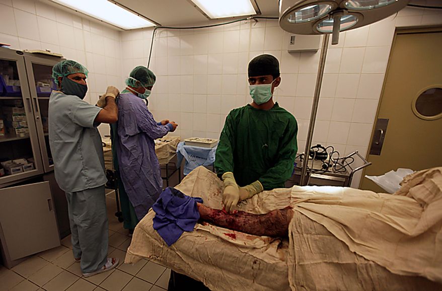In this Saturday, Aug. 7, 2010 photo, Afghan army doctors and medics prepare for emergency surgery on a wounded Afghan soldier, at Kandahar Regional Military Hospital, KRMH, inside Camp Hero, Kandahar province, southern Afghanistan. The names of the Afghan doctors are withheld for their protection. A U.S Air Force Medical Training Advisory Group, or MTAG team, comprised of 12 medical professionals, is assigned to the Afghan military hospital, and are tasked with providing transitional guidance to local medical workers, who treat Afghan soldiers, civilians, and occasionally insurgents. (AP Photo/Brennan Linsley)