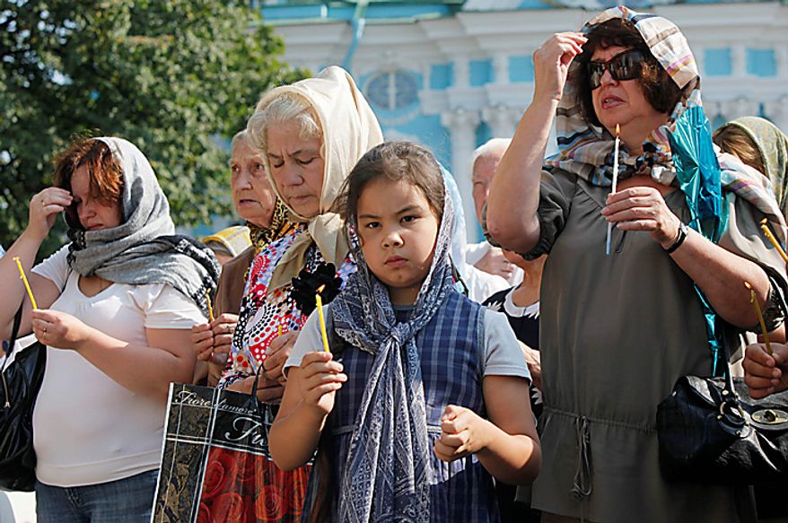 People pray outside the St. Nicolas Cathedral, place, where the list of submarine disaster victims is displayed, in St.Petersburg, Russia, Thursday, Aug. 12, 2010. Russian navy ships are flying flags at half-mast and memorial ceremonies are being held across the nation to commemorate the 10th anniversary of the Kursk nuclear submarine disaster. (AP Photo/Dmitry Lovetsky)