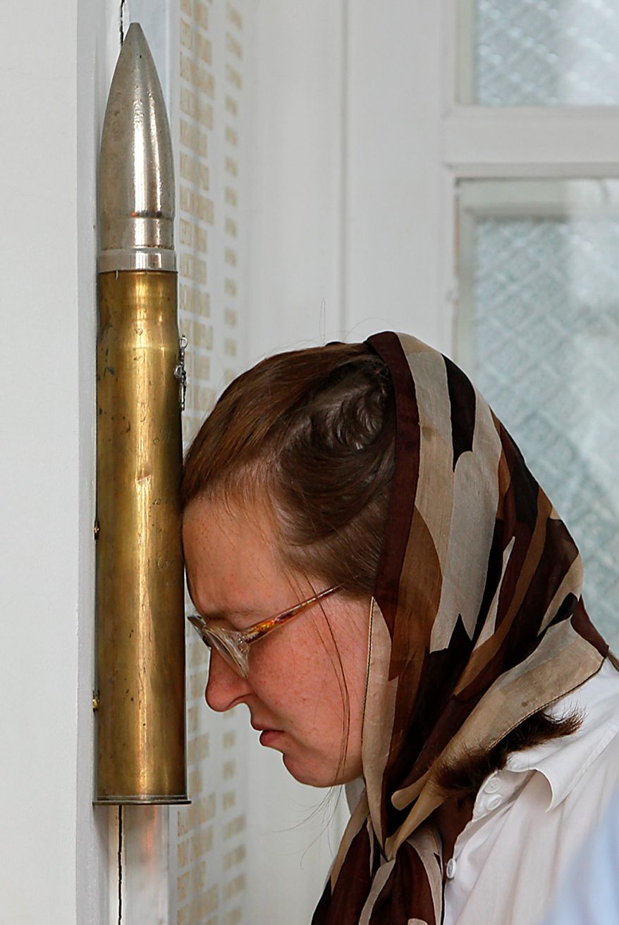 A woman touches a shell, Thursday, Aug. 12, 2010, in the St. Nicolas Cathedral, in St. Petersburg, Russia, filled with the soil from the sea bottom where the submarine disaster Kursk took place. Russian navy ships are flying flags at half-mast and memorial ceremonies are being held across the nation to commemorate the 10th anniversary of the Kursk nuclear submarine disaster. (AP Photo/Dmitry Lovetsky)