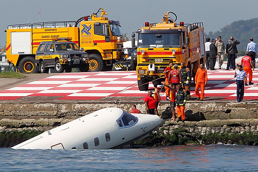 Workers try to pull a small jet from the ocean in Guanabara Bay after it crashed at Rio de Janeiro's domestic airport, Brazil, Thursday, Aug. 12, 2010. All three people aboard survived. The Sugar Loaf mountain stands at back. (AP Photo/Felipe Dana)