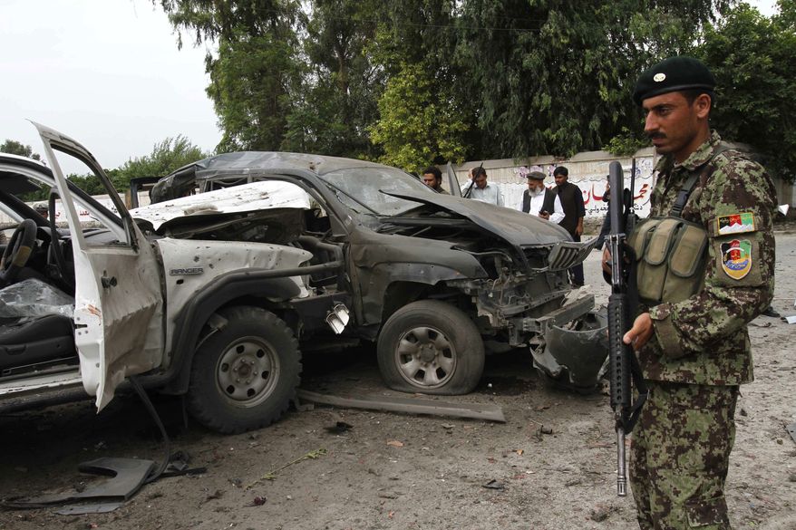 ** FILE ** In this Aug. 2, 2010, file photo, Afghans gather at the scene of an attack on a presidential adviser in Jalalabad, east of Kabul, Afghanistan. Militants attacked the second government official in the east on the same day. The convoy was hit by a remote-controlled bomb hidden in a rickshaw as it was driving through city, police said. (AP Photo/Rahmat Gul, File)