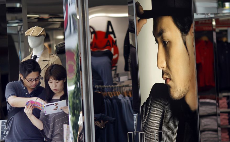 Tourists stop at a clothing shop in Tokyo Monday, Aug. 16, 2010. Japan lost its place as the world's No. 2 economy to China in the second quarter as receding global growth sapped momentum and stunted a shaky recovery. (AP Photo/Junji Kurokawa)