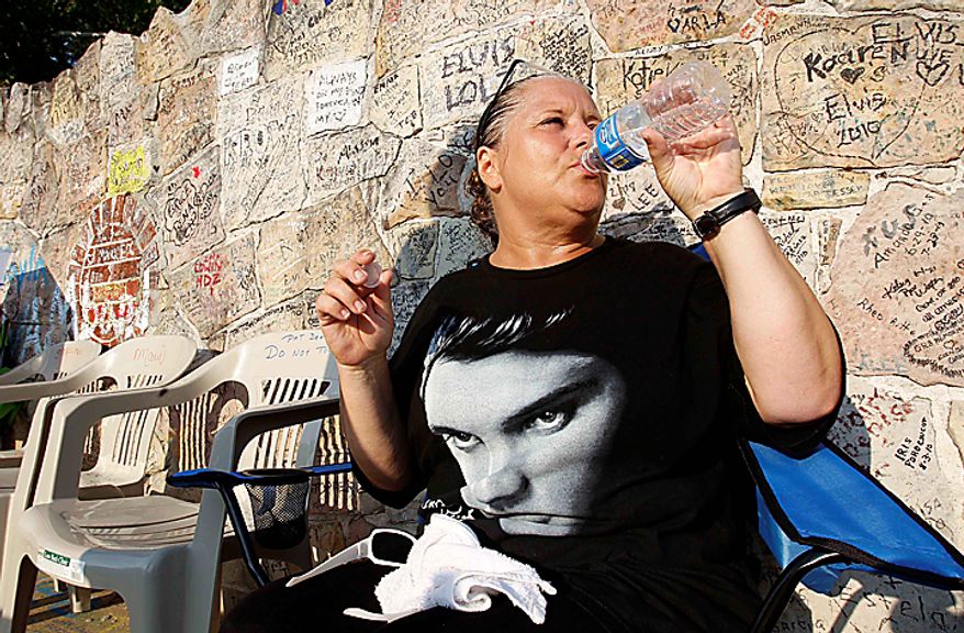 Elvis Presley fan Jeanine Hendershot, of Rocky Mount, N.C., drinks water as she waits in the heat outside Graceland mansion on Sunday, Aug. 15, 2010, in Memphis, Tenn. Presley fans from around the world are at Graceland for the annual nighttime procession past his grave on the eve of his death. Presley died at the home Aug. 16, 1977. (AP Photo/Mark Humphrey)