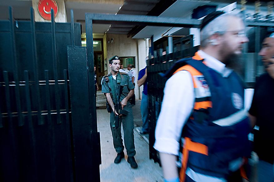 An Israel border police officer holds his weapon as a paramedic rushes put of the Turkish Embassy in Tel Aviv, Israel, Tuesday, Aug. 17, 2010. A Palestinian took hostages in the Turkish Embassy in Tel Aviv Tuesday after shots were fired outside, Israeli police and a Foreign Ministry official said, in an incident that appeared to have only an indirect link to recent tensions between the two countries. (AP Photo / Ariel Schalit)