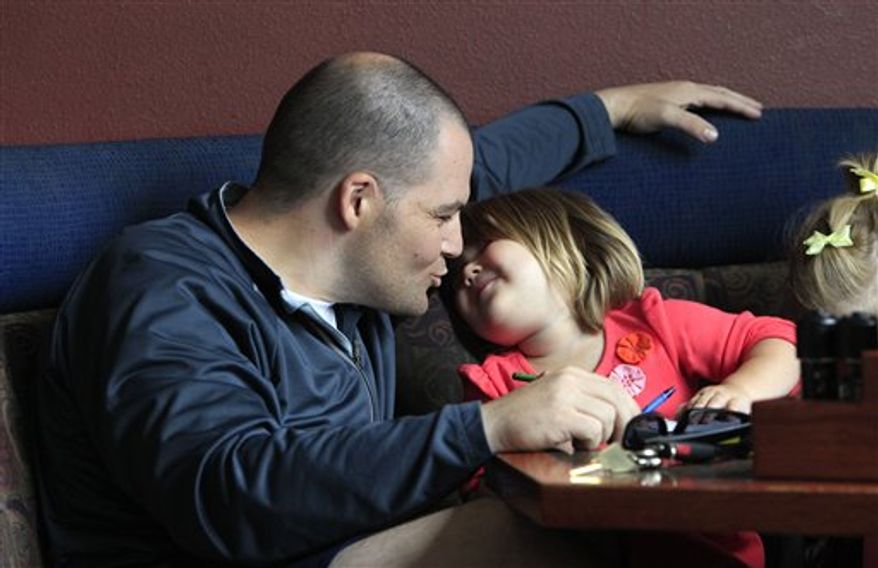 U.S. Army Capt. Mark Fisher, left, leans down to kiss his daughter Madeline, 2, as he sits to have lunch with her and another daughter after arriving at nearby Joint Base Lewis-McChord the evening before Thursday, Aug. 19, 2010, in DuPont, Wash. Fisher had just returned from a nearly one-year tour in Iraq, his second there. Seven years and five months after the U.S.-led invasion, the last American combat brigade was leaving Iraq, well ahead of President Barack Obama's Aug. 31 deadline for ending U.S. combat operations there. (AP Photo/Elaine Thompson)