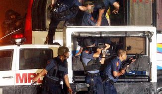Police and SWAT members rush a tourist bus to rescue hostages on Monday in Manila, Philippines. Rolando Mendoza, an ex-policeman armed with an automatic rifle, seized the bus and demanded reinstatement. (Associated Press)