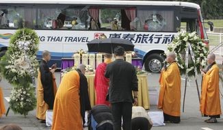 Relatives of the eight Hong Kong tourists who were killed in the tourist bus hostage crisis, kiss the ground near the bullet-riddled tourist bus during a Buddhist ceremony Tuesday, Aug. 24, 2010, at Rizal Park in Manila, Philippines. The Chinese authorities demanded answers from the Philippines on Tuesday after a 12-hour hostage drama in the heart of Manila ended with eight Hong Kong tourists and their Filipino hostage-taker dead following a day of botched negotiations. (AP Photo/Bullit Marquez)
