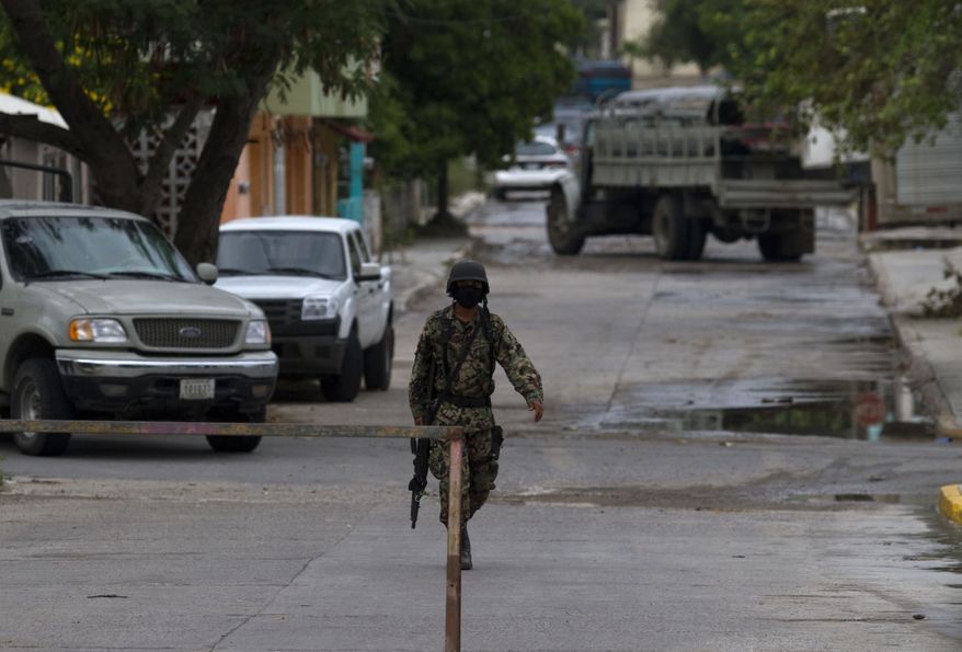 A navy officer guards a street where a funeral home is holding the bodies of 72 men and women that were purportedly killed by the Zetas drug gang are in San Fernando, just 100 miles from the the Mexican border with the U.S. near the city of Matamoros, Mexico, Thursday Aug. 26, 2010. A wounded migrant who escaped the Zetas gang stumbled into a military checkpoint and led marines to the scene were migrants from Brazil, Ecuador, El Salvador and Honduras were executed. (AP Photo/Guillermo Arias)
