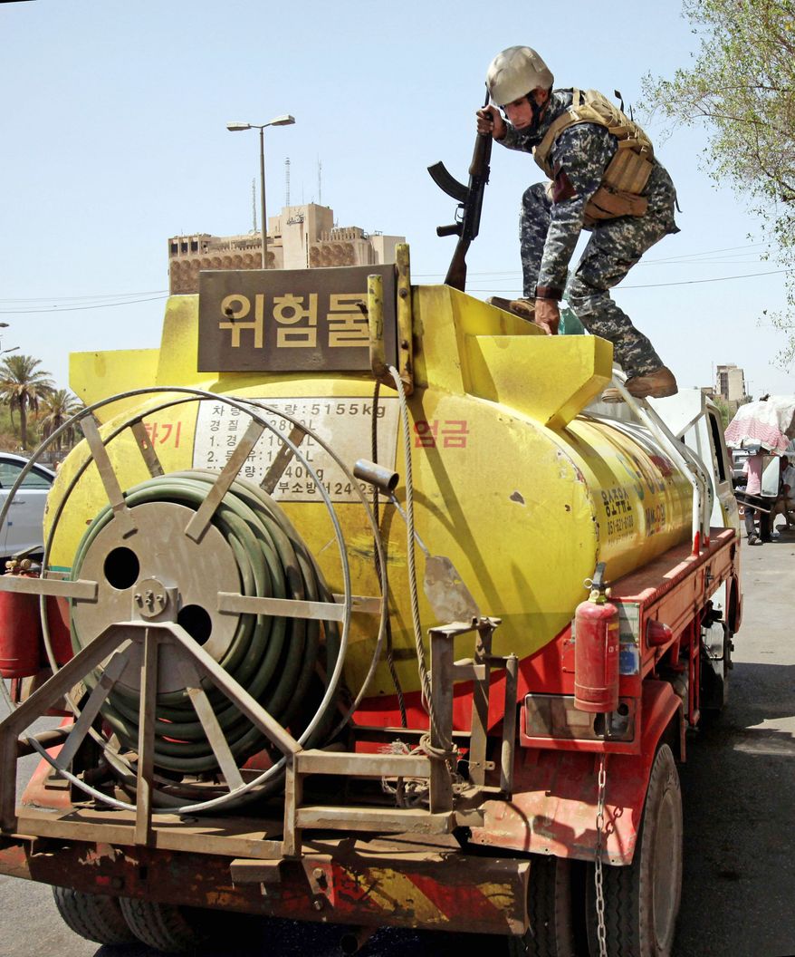 ON TOP OF IT: An Iraqi police officer searches a fuel tanker Sunday in Baghdad. Iraqi troops are poised to take over security, but some U.S. special operations forces will remain. (Associated Press)