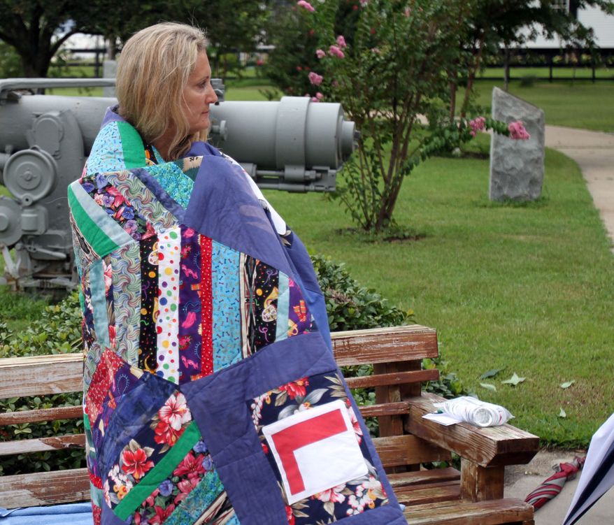 Mariah Furze wraps herself in her Hurricane Katrina blanket during a hurricane remembrance ceremony at War Memorial Park in Pass Christian, Miss., on Saturday, Aug. 28, 2010. The blanket was made from pieces of cloth found after Katrina. (AP Photo/Sun Herald, Tim Isbell)