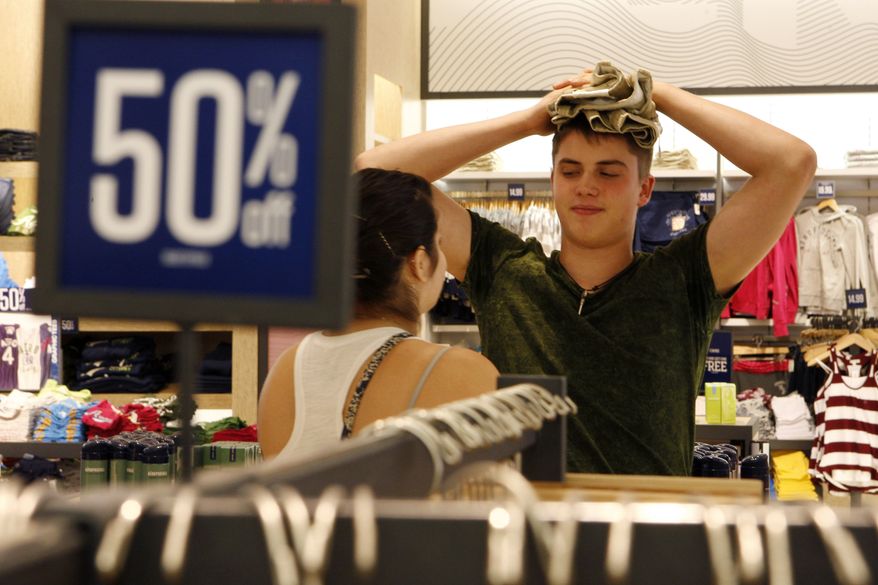 Carine Abraham and Austin Savill, both 19, stand in line near a 50 percent off sign as they wait to make a purchase at an Aeropostale store in Paramus, N.J., on July 27, 2010. Consumer spending rose 0.4 percent in July after three lackluster months, the Commerce Department said Monday. (AP Photo/Mel Evans)