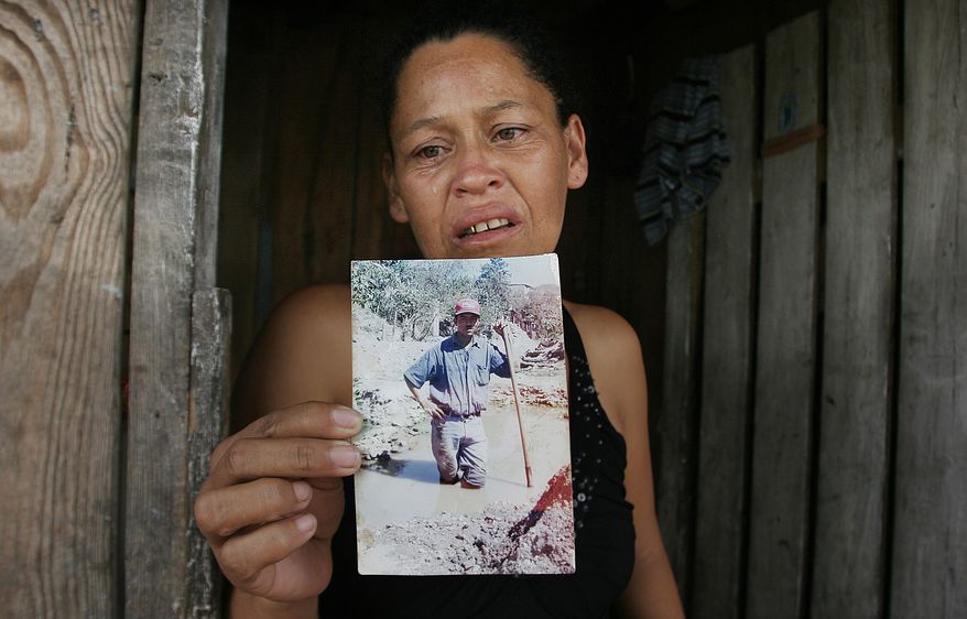 Marleni Xiomara Suarez Ortega, weeps as she speaks to the press while holding up a photo of her late husband, Miguel Angel Carcamo, outside of her home in Tegucigalpa, Honduras Saturday Aug. 28, 2010. Her husband purportedly was among the 72 migrants killed in northern Mexico by, what could be, a gang of drug traffickers.(AP Photo/Fernando Antonio)
