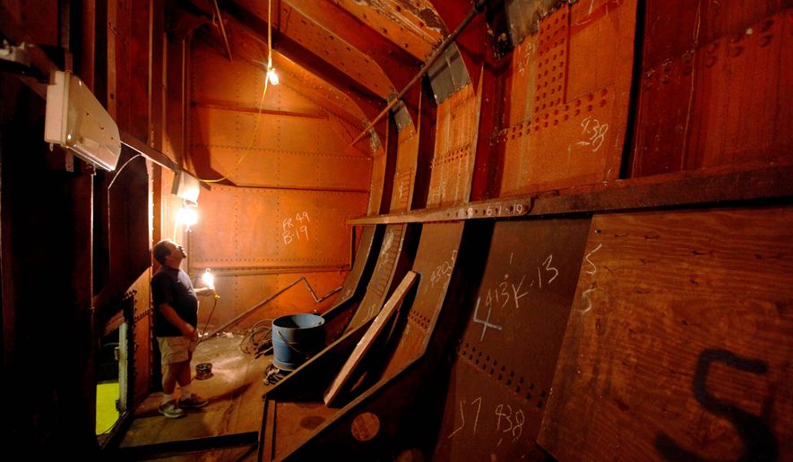 Jesse Lebovics, longtime caretaker of the 1892 USS Olympia, the oldest steel warship still afloat, illuminates a coal bunker to show multiple repairs at and below the waterline. The museum ship, in the Delaware River, needs $1 million to survive. (Associated Press)