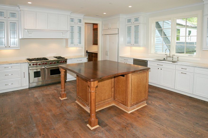 The kitchen features a furniture-grade center island with a breakfast bar, a walk-in pantry, granite counters and glass-front cabinets.