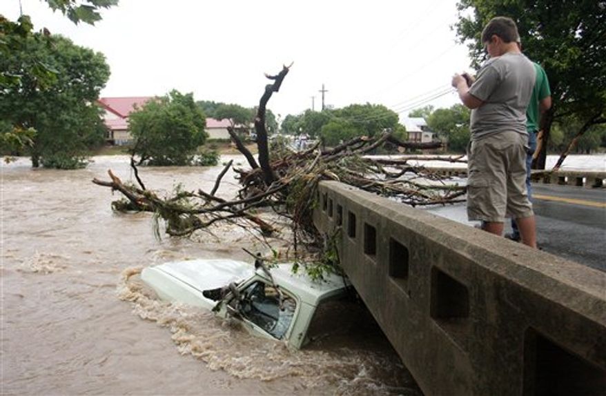 Visitors to Salado, Texas snap photos of a submerged truck under the main street bridge on Wednesday morning, Sept. 8, 2010 as waters begin to receed from excessive rainfall caused by Tropical Storm Hermine. (AP Photo/Temple Daily Telegram, Rusty Schramm) MANDATORY CREDIT; TV OUT