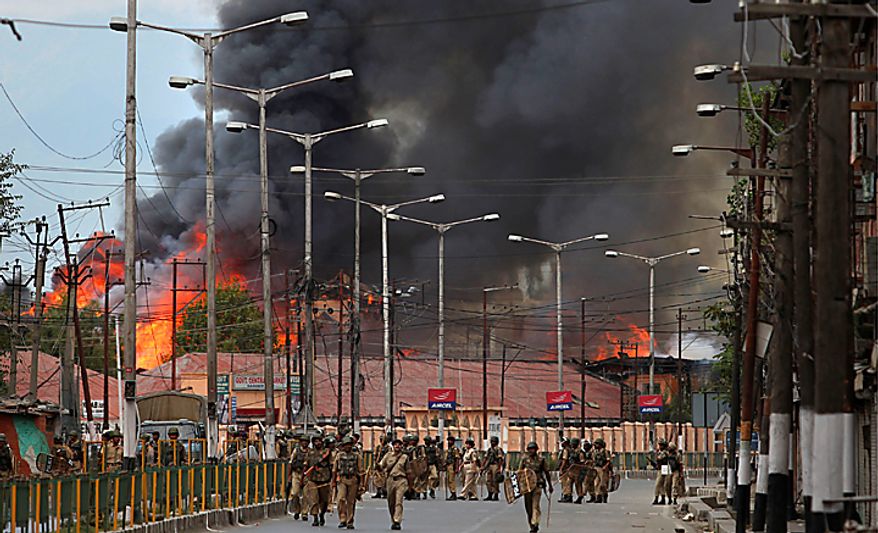 Indian forces patrol as flames rise from a government building set on fire by protesters in Srinagar, India, Saturday, Sept. 11, 2010. Police fired warning shots and tear gas to disperse hundreds of demonstrators who attacked a police post and burned government offices in Kashmir on Saturday, as tens of thousands of people took to the streets to protest Indian rule in the Himalayan region, officials said. (AP Photo/Altaf Qadri)