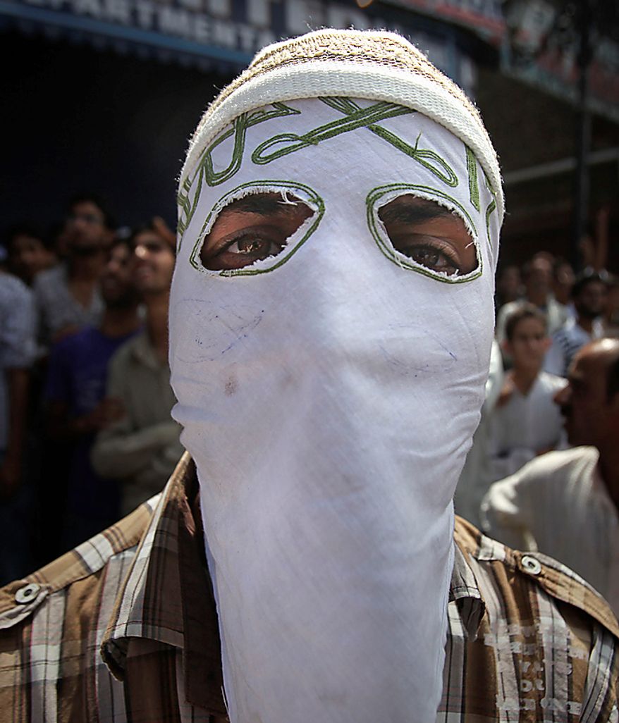 A masked Kashmiri protestor looks on during a protest rally after Eid al-Fitr prayers in Srinagar, India, Saturday, Sept. 11, 2010. Police fired warning shots and tear gas to disperse hundreds of demonstrators who attacked a police post and burned government offices in Kashmir on Saturday, as tens of thousands of people took to the streets to protest Indian rule in the Himalayan region, officials said. (AP Photo/Altaf Qadri)