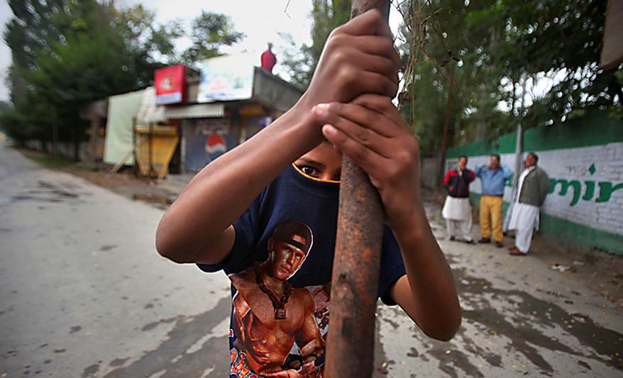 A young Kashmiri protester covers his face with his Tee shirt as he holds an effigy of Indian prime minister during a protest in Srinagar, India, Tuesday, Sept. 14, 2010. Indian police patrolled the streets of Kashmir on Tuesday, threatening to shoot anyone defying a rigid curfew imposed on the region a day after troops battled protesters in the streets in violence that killed several people. (AP Photo/Altaf Qadri)