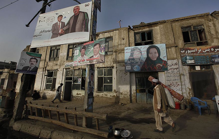 An Afghan man, carrying a floor mat, walks past election campaign billboards in Kabul, Afghanistan, Friday, Sept. 17, 2010. Police set up extra checkpoints across Afghanistan on Friday to scan for suicide bombers and insurgents a day ahead of parliamentary polling. (AP Photo/Gemunu Amarasinghe)