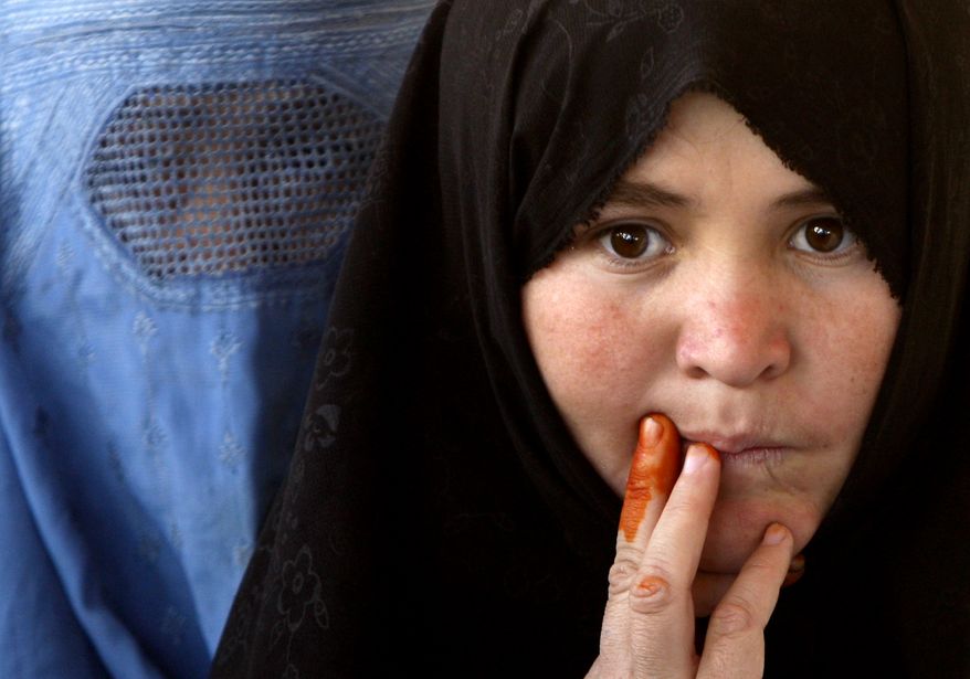 Afghan women wait outside a polling station to cast their ballots for the parliamentary elections in Mazar-e-Sharif, Balkh province, north of Kabul, Afghanistan, Saturday, Sept. 18, 2010. Afghans braved Taliban rockets and polling site bombings Saturday to vote for a new parliament in elections seen as a measure of the government's competence and commitment to democratic rule. It was the first nationwide balloting since a fraud-marred presidential election last year undermined international support for President Hamid Karzai.The ink on the woman's finger is from traditional henna. (AP Photo/ Mustafa Quraishi)