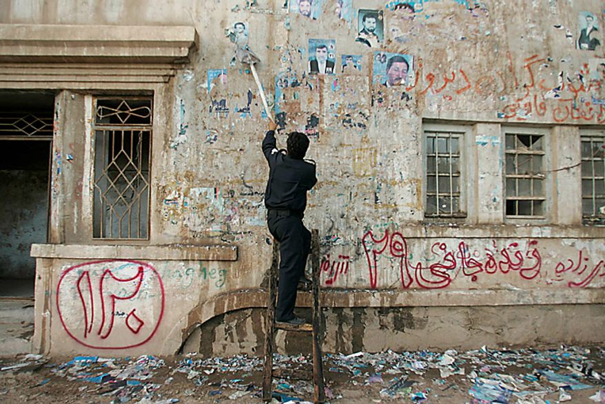 A policeman scrapes a wall clean of posters of candidates who contested in the parliamentary elections, in Herat, Afghanistan, Monday Sept. 20, 2010. Afghan election observers urged President Hamid Karzai's government on Monday to allow an independent investigation into reports of widespread fraud during last weekend's parliamentary elections, including intimidation of voters and interference by powerful warlords. (AP Photo/ Reza Shirmohammadi)