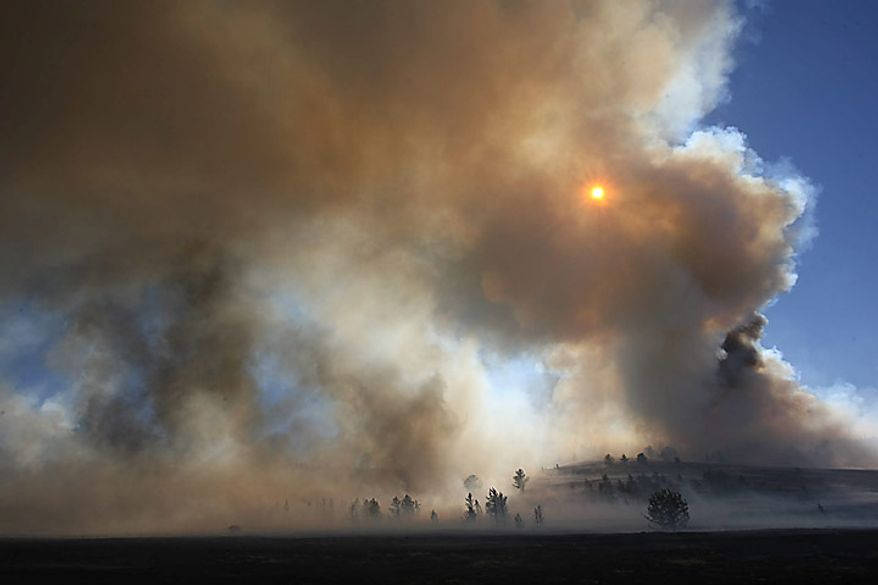 The sun illuminates heavy smoke billowing out of Roger's Canyon Sunday Sept. 19, 2010 10 miles northeast of Laramie, Wyo. (AP Photo/Laramie Boomerang, Andy Carpenean)