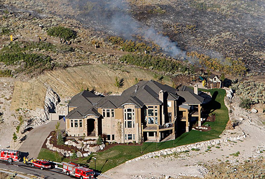 Fire continues to burn near homes in Herriman, Utah on Monday, Sept. 20, 2010. A wind-stoked wildfire sparked at a firing range during a National Guard training session blazed across thousands of acres Monday as crews rushed to keep it from burning more than four homes that were destroyed overnight. The fire moved back on itself Monday as the Utah National Guard acknowledged it wasn't the first time that live-fire exercises had sparked a fire at Camp Williams, a sprawling compound 30 miles south of Salt Lake City. (AP Photo/Scott G Winterton, Pool)