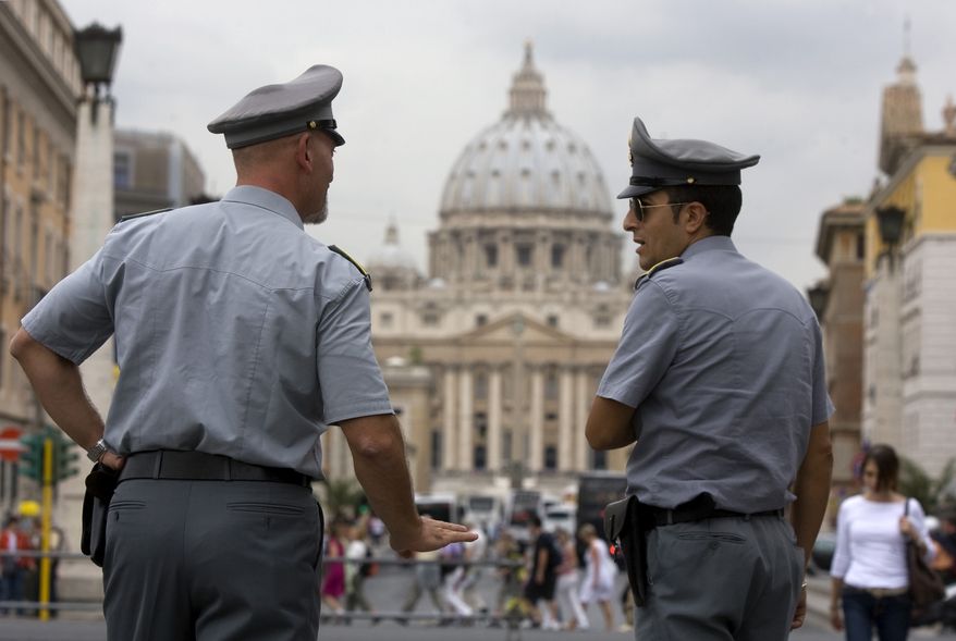 Italian financial police officers talk with each other in front of St. Peter's Square at the Vatican on Tuesday, Sept. 21, 2010. Italian authorities have seized 23 million euros ($30.18 million) from a Vatican bank account and begun investigating top officials of the bank in connection with a money-laundering probe. (AP Photo/Angelo Carconi)