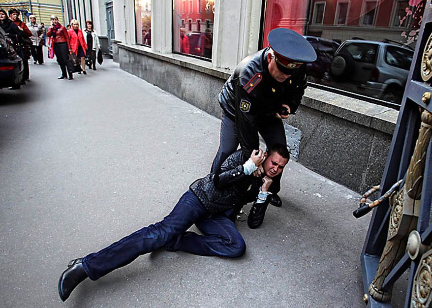 Police officer detains a gay rights activist during a rally near city hall in Moscow, Tuesday, Sept., 21, 2010. Moscow police has dispersed a gay rally and detained activists protesting homophobic policies of Moscow authorities. Mayor Yuri Luzhkov has called homosexuals "satanic" and routinely thwarted their attempts to hold a gay pride in Moscow. Police officers detained on Tuesday at least a dozen activists in a Moscow square near the city hall minutes after they brought out a papier-mache mummy that resembled Luzhkov and unfurled posters ridiculing him. (AP Photo/Sergey Ponomarev)