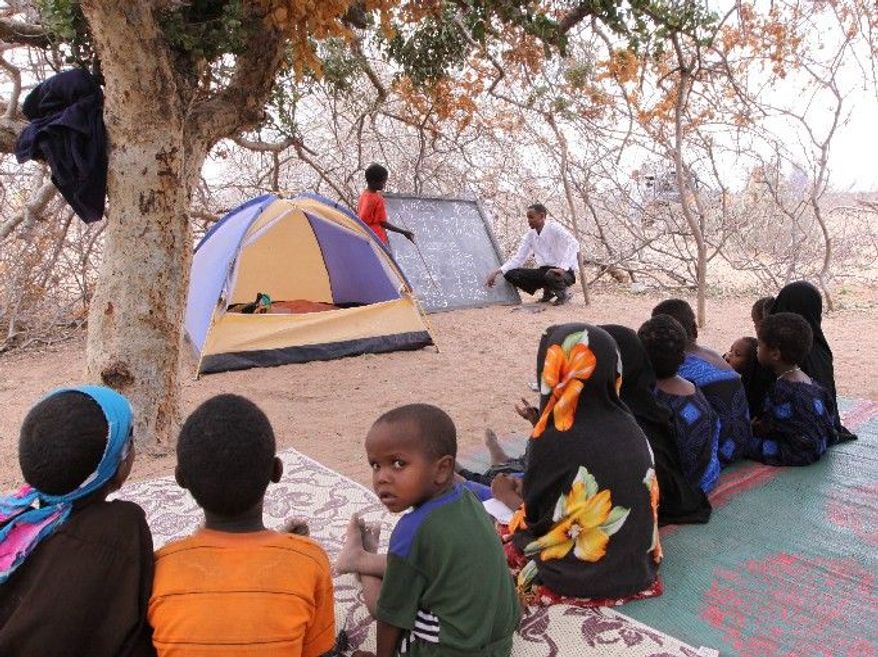 Children study in scant shade in Dertu, where school attendance has doubled for boys and tripled for girls. Their teacher lives in a backpacker's tent and will move with the nomads when they do. (Associated Press)