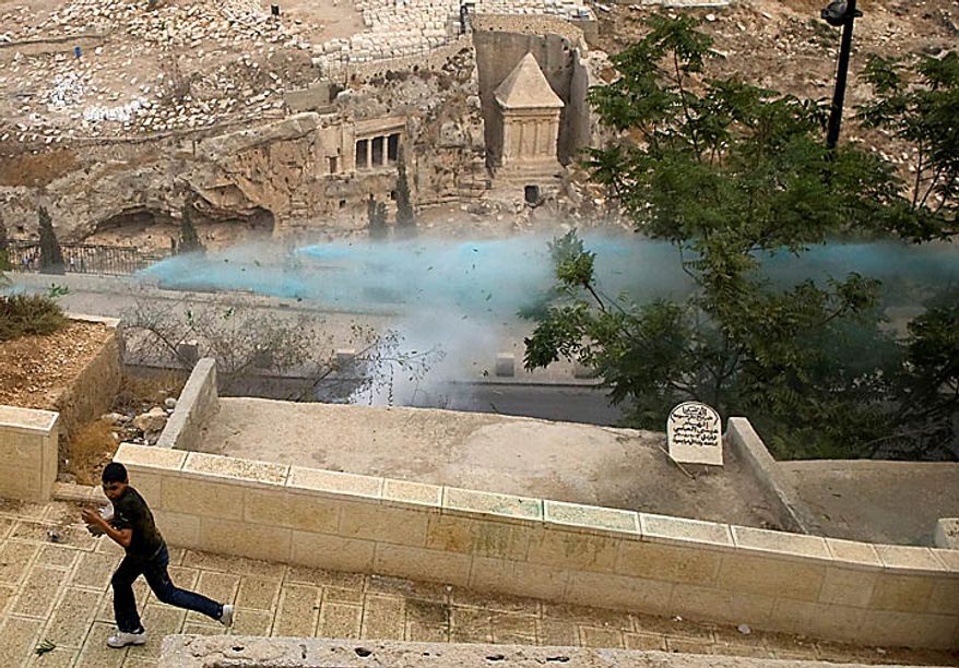 A Palestinian youth runs from a police colored water canon during clashes outside Jerusalem's Old City, Wednesday, Sept. 22, 2010. Violence erupted after a 32-year-old Palestinian laborer was killed by a private security guard watching over Jewish families in the Silwan neighborhood in east Jerusalem. During the man's funeral, a mob of protesters set tires on fire, smashed the windows of several buses and called for revenge. (AP Photo/Sebastian Scheiner)