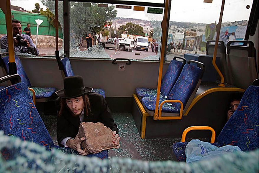 Two ultra-Orthodox Jewish men protect themselves inside a bus from Palestinian rioters outside Jerusalem's Old City, Wednesday, Sept. 22, 2010. Violence erupted after a 32-year-old Palestinian laborer was killed by a private security guard watching over Jewish families in the Silwan neighborhood in east Jerusalem. During the man's funeral, a mob of protesters set tires on fire, smashed the windows of several buses and called for revenge. (AP Photo/Bernat Armangue)