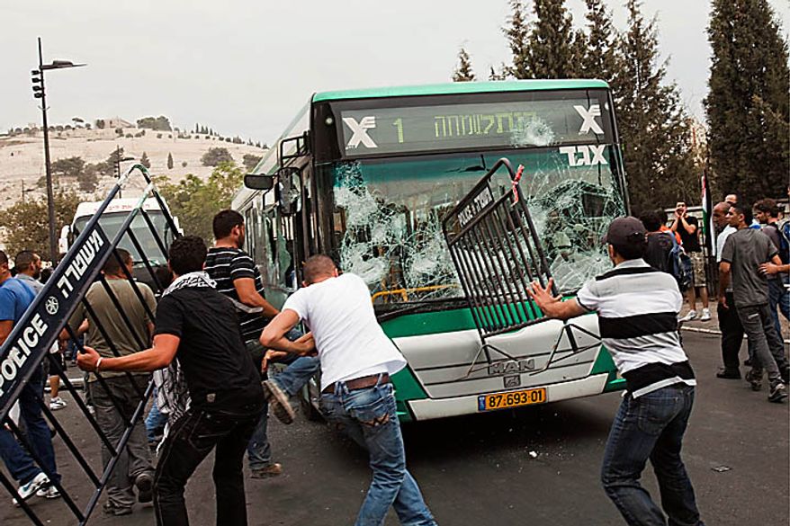 Palestinians smash the windows of a bus outside Jerusalem's Old City, Wednesday, Sept. 22, 2010. Violence erupted after a 32-year-old Palestinian laborer was killed by a private security guard watching over Jewish families in the Silwan neighborhood in east Jerusalem. During the man's funeral, a mob of protesters set tires on fire, smashed the windows of several buses and called for revenge. (AP Photo/Bernat Armangue)