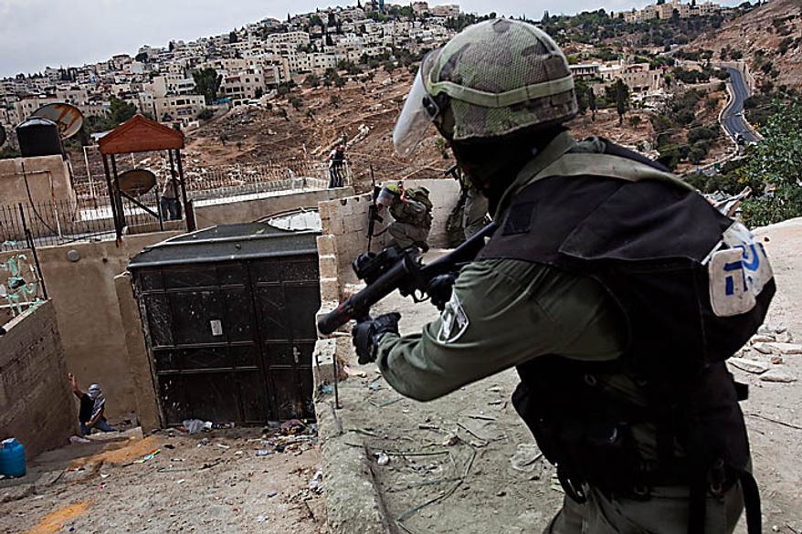 A Palestinian rioter, left, throws a stone at Israeli border police during clashes in the east Jerusalem neighborhood of Silwan, Wednesday, Sept. 22, 2010. Violence erupted after a 32-year-old Palestinian laborer was killed by a private security guard watching over Jewish families in the Silwan neighborhood in east Jerusalem. During the man's funeral, a mob of protesters set tires on fire, smashed the windows of several buses and called for revenge. (AP Photo/Bernat Armangue)