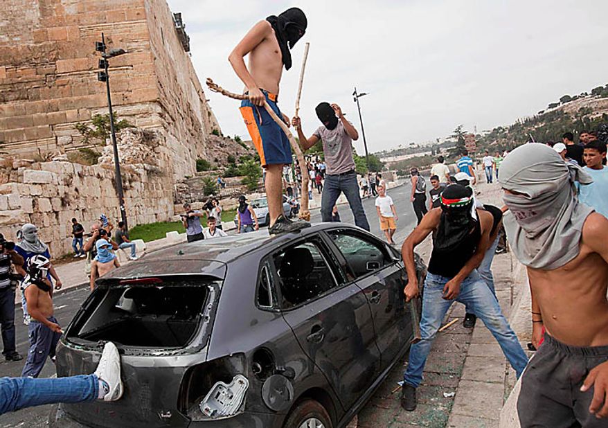 Palestinians vandalize a car outside Jerusalem's Old City, Wednesday, Sept. 22, 2010. Violence erupted after a 32-year-old Palestinian laborer was killed by a private security guard watching over Jewish families in the Silwan neighborhood in east Jerusalem. During the man's funeral, a mob of protesters set tires on fire, smashed the windows of several buses and called for revenge. (AP Photo/Bernat Armangue)