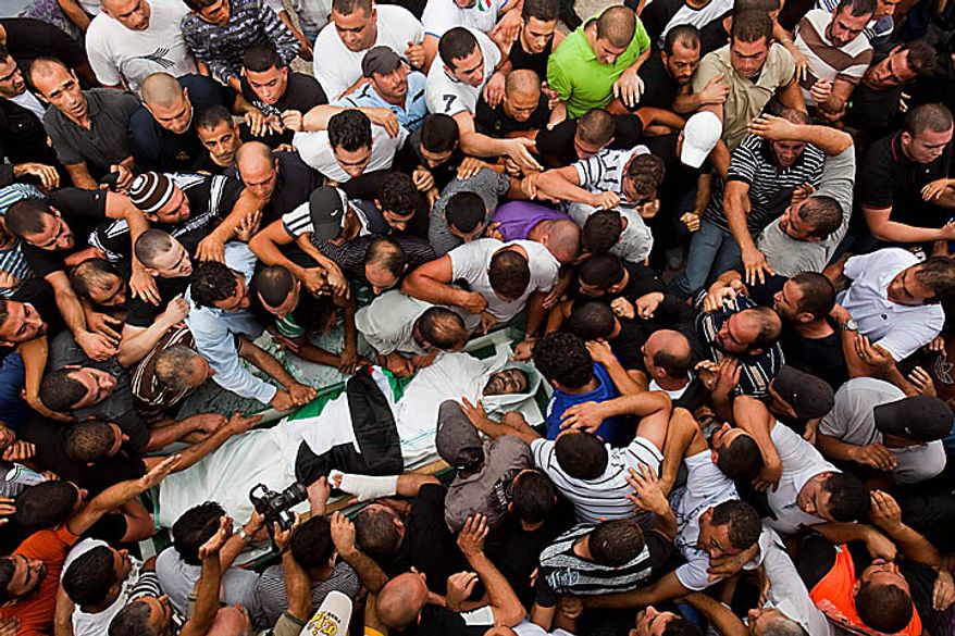 Palestinian mourners carry the coffin of Sami Sirhan during his funeral in the east Jerusalem neighborhood of Silwan, Wednesday, Sept. 22, 2010. Sirhan, a 32-year-old Palestinian laborer was killed by a private security guard watching over Jewish families in the Silwan neighborhood in east Jerusalem. During his funeral, a mob of protesters set tires on fire, smashed the windows of several buses and called for revenge. (AP Photo/Bernat Armangue)