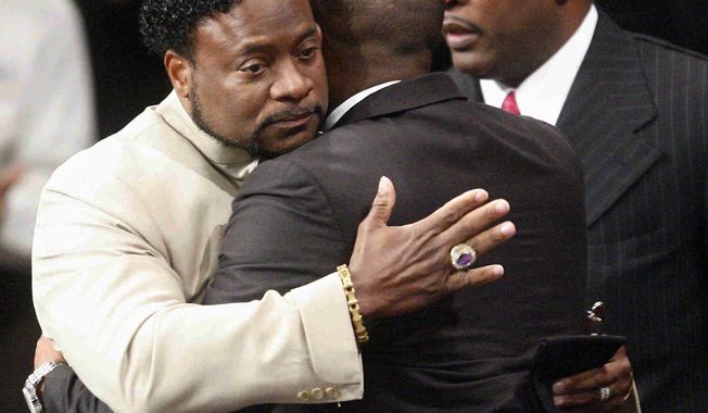 Bishop Eddie Long (left) embraces an attendee at services at the New Birth Missionary Baptist Church outside Atlanta on Sunday, Sept. 26, 2010. Bishop Long, the pastor of the Georgia megachurch, who is accused of luring young men into sexual relationships, told his congregation of thousands that all people must face painful and distasteful situations. (AP Photo/John Amis, Pool)